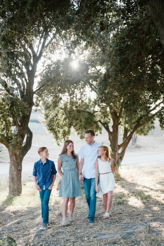 A family standing together beneath trees on a sandy path