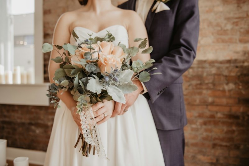 Bride holding a soft blush bouquet beside the groom