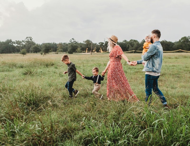 A family walking hand in hand through a grassy field