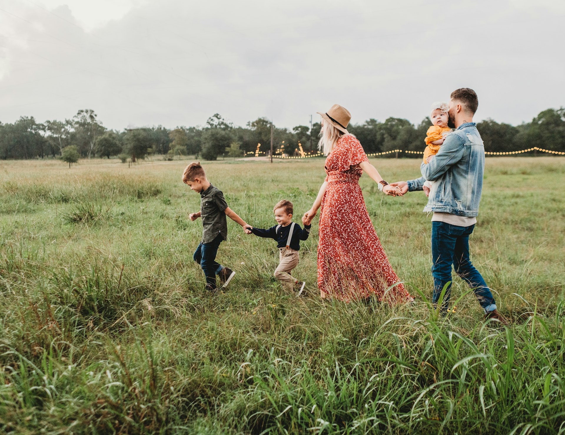 A family walking hand in hand through a grassy field