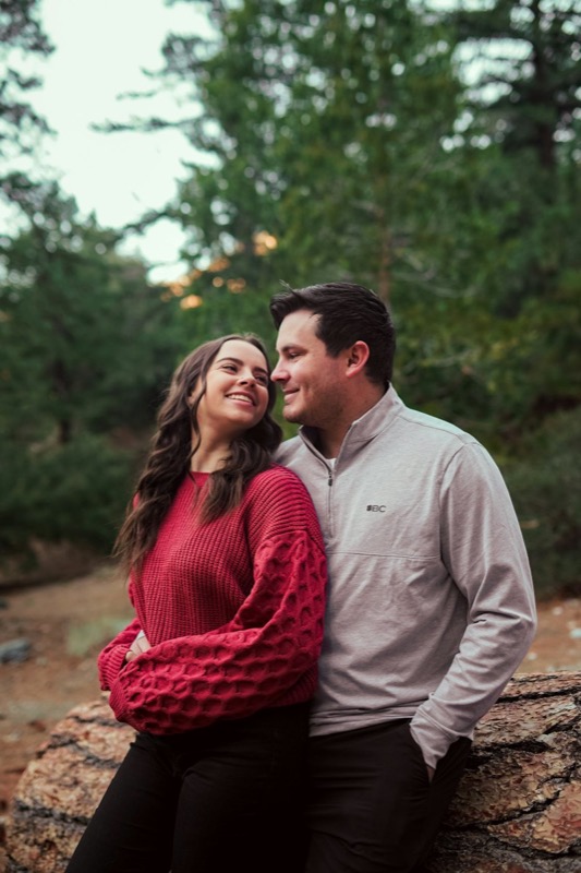 A couple sitting together on a rock among the pines