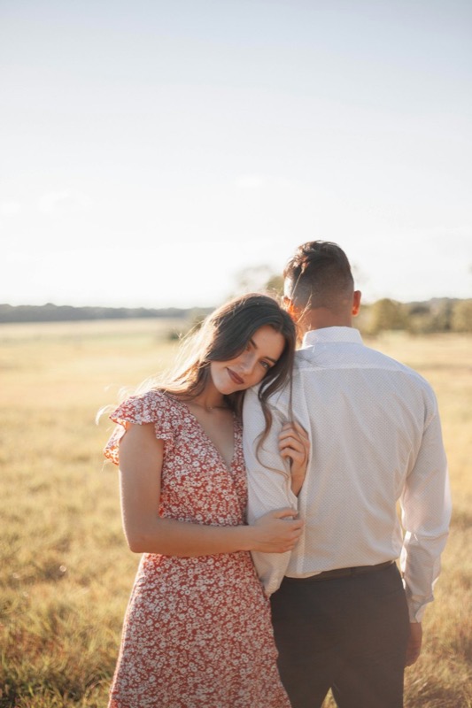 A man kissing a woman in a floral dress in a summer meadow