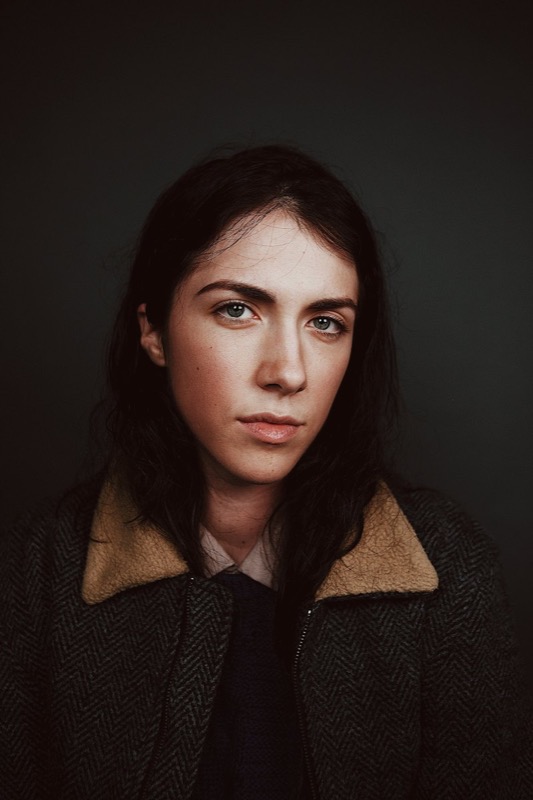 Portrait of a woman in a shearling coat against a dark backdrop
