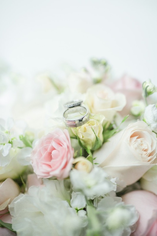 A wedding ring nestled in white and pink roses