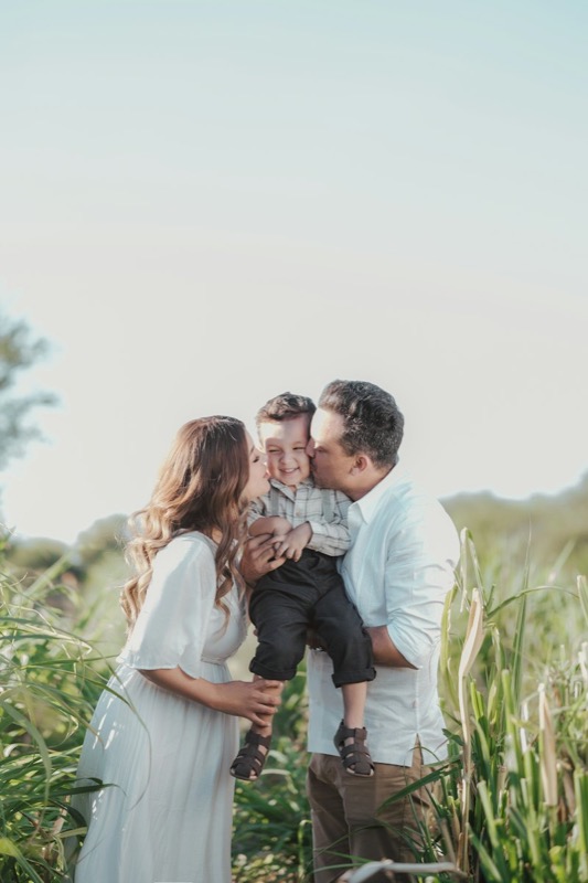 Parents holding their child in a field of tall grass