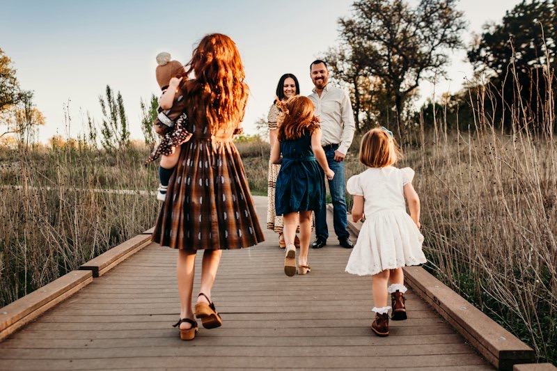 A family walking along a wooden boardwalk at golden hour