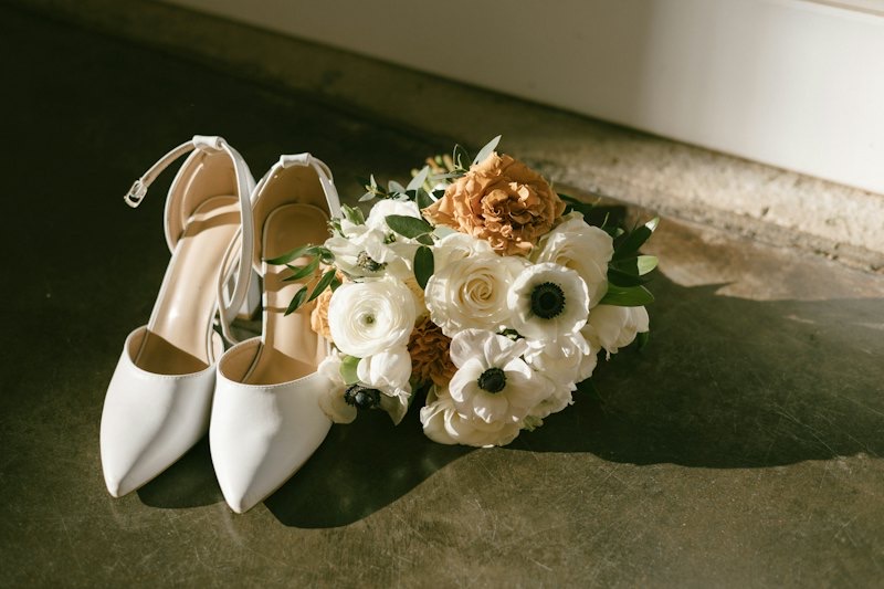 Bridal shoes resting beside a white bouquet