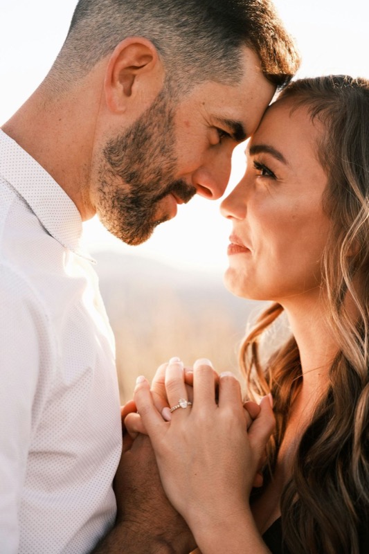 Close portrait of a couple touching foreheads, hands clasped