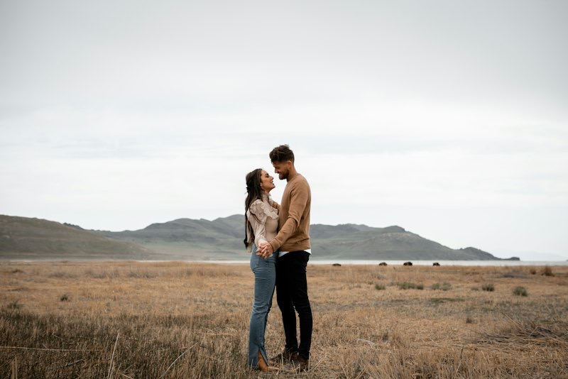 A couple embracing in an open field by the coast