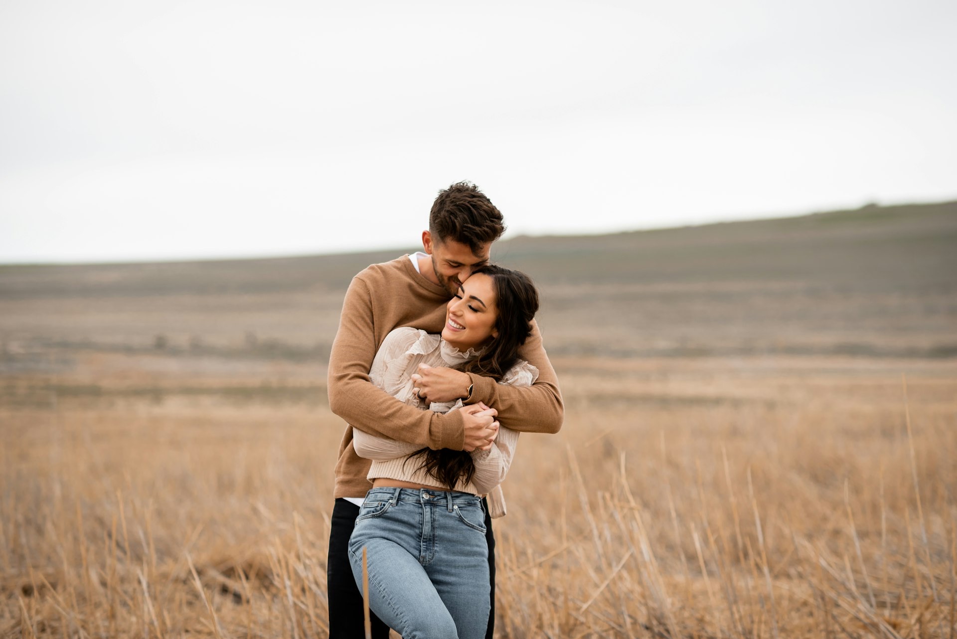 A couple hugging in a wide open golden field
